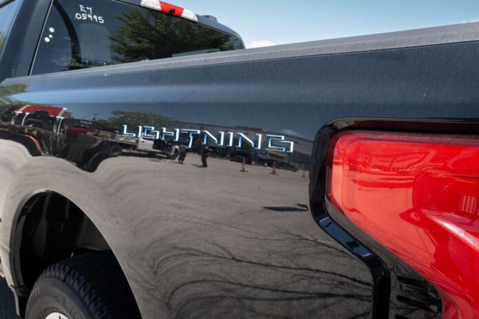  The Lightning badge is shown on a Ford F-150 Lightning electric pickup truck being offered for sale at a dealership 