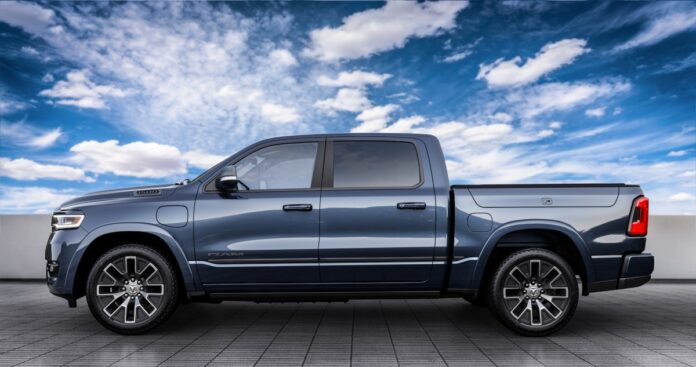 A side shot of a smoky blue 2025 Ram 1500 Ramcharger Tungsten with clouds and blue sky in the background